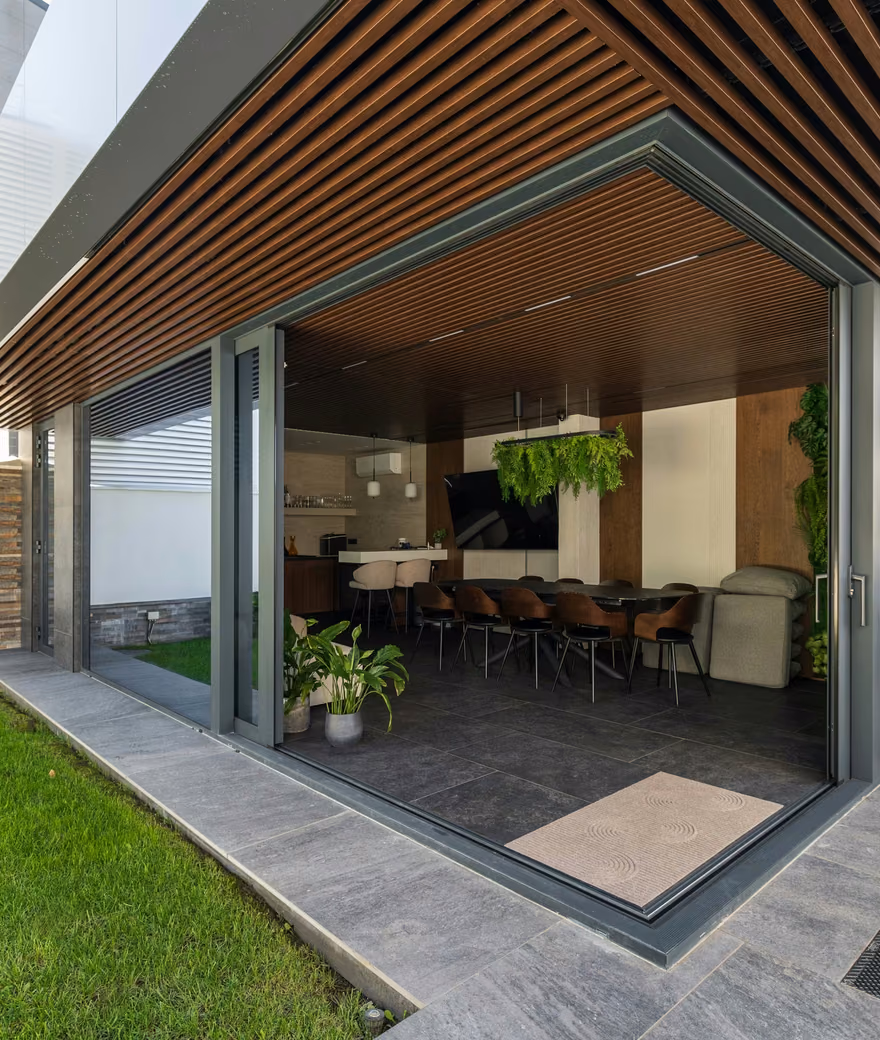 Terasă contemporană cu suprafețe vitrate panoramice și profile din aluminiu închise la culoare.