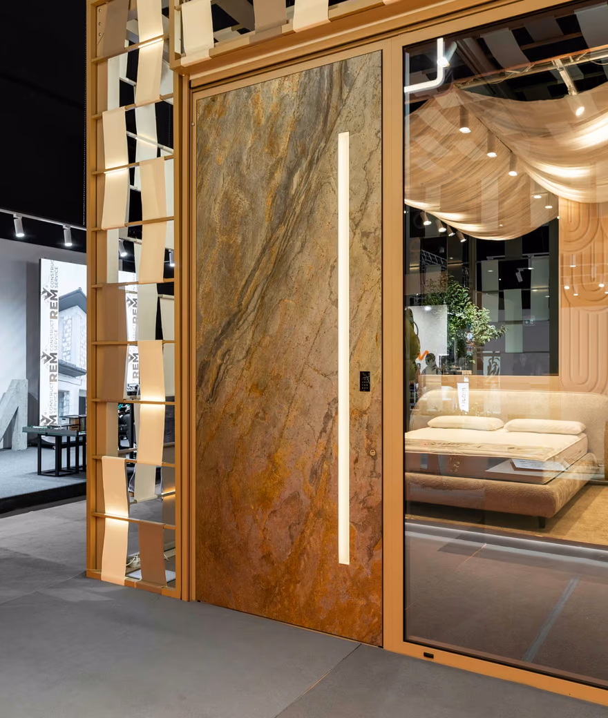 Stand expozițional Plastregal cu panou de ușă cu aspect de piatră, vitraje ample și structură decorativă din lemn.