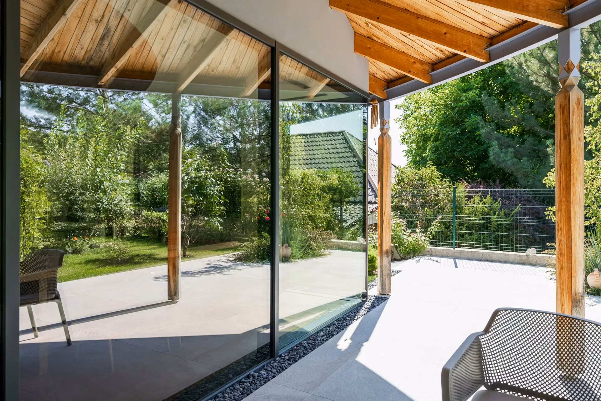 Panoramic glazed corner beneath a timber roof overlooking the garden.