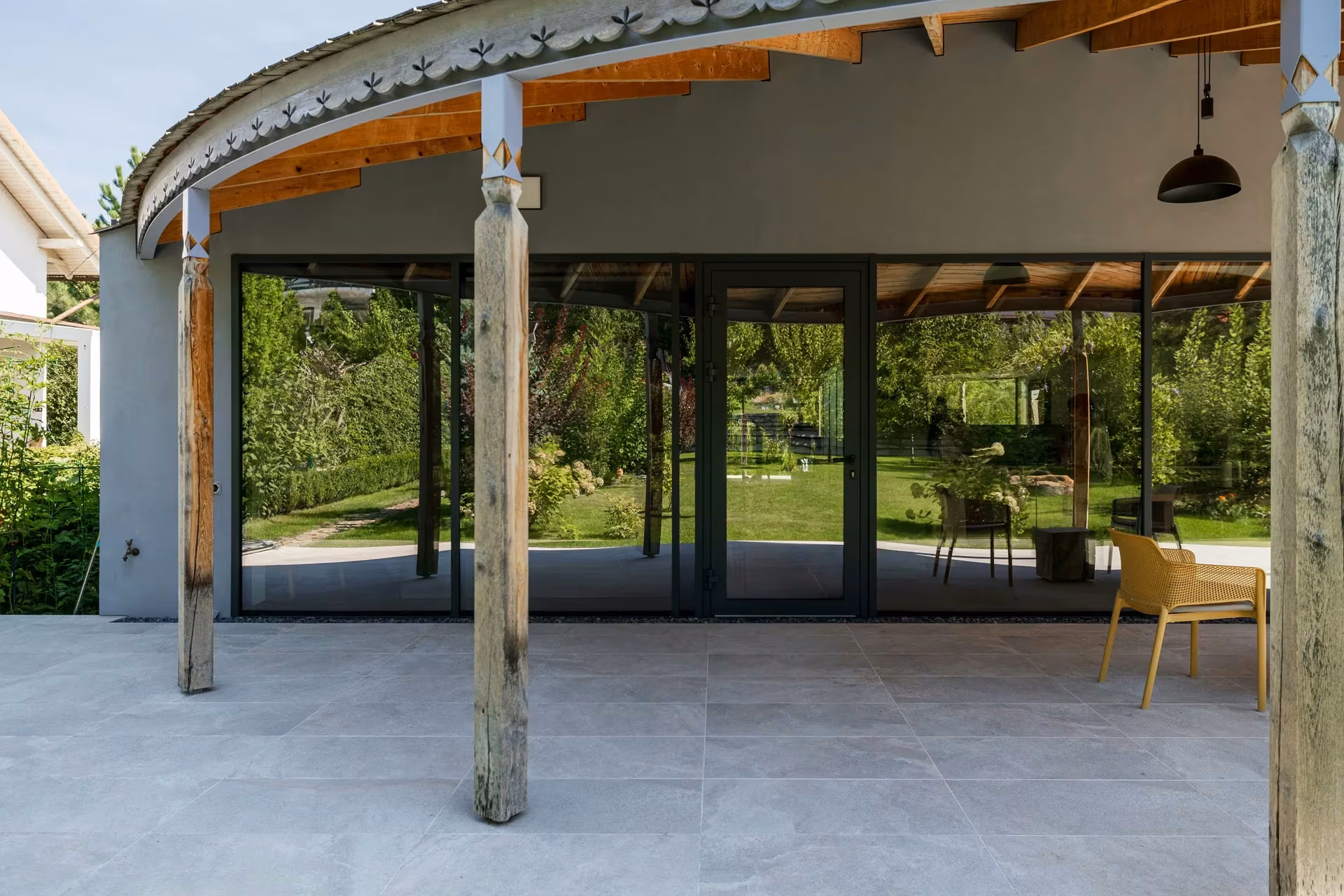Curved glazed facade framed by timber columns along the terrace.