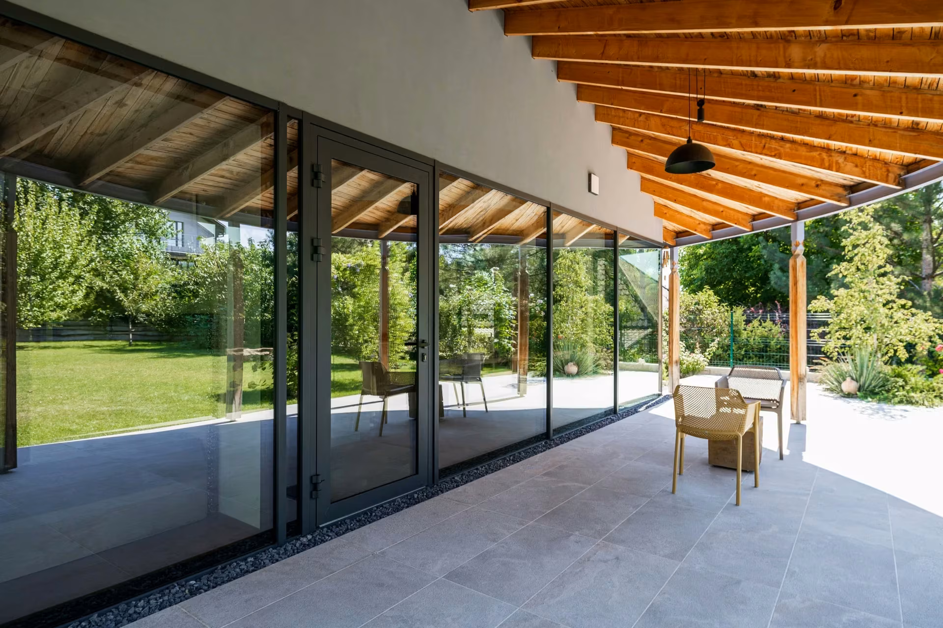 Side facade with tall glazed panels beneath a timber roof structure.