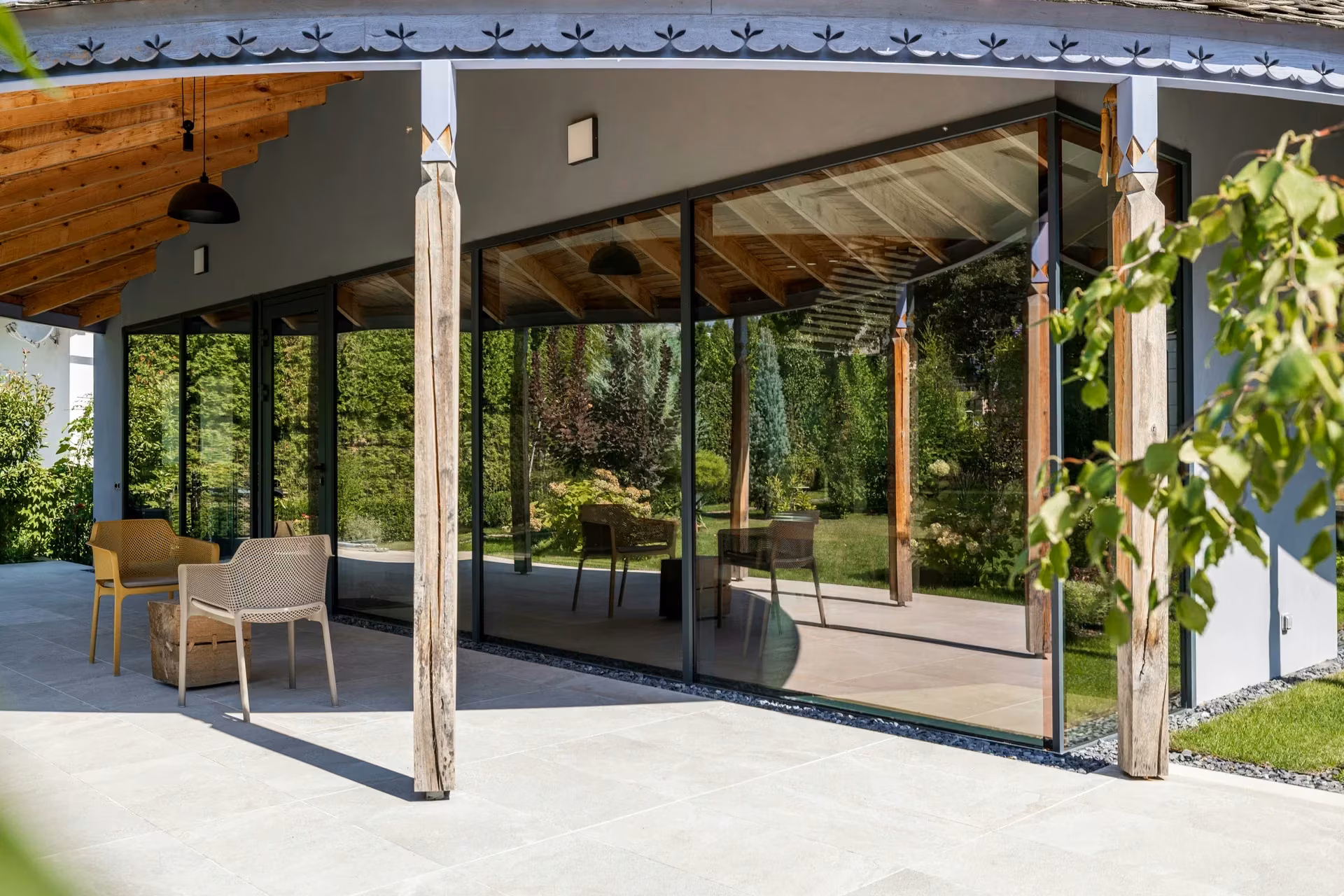 Panoramic corner glazing with timber columns and a covered terrace.