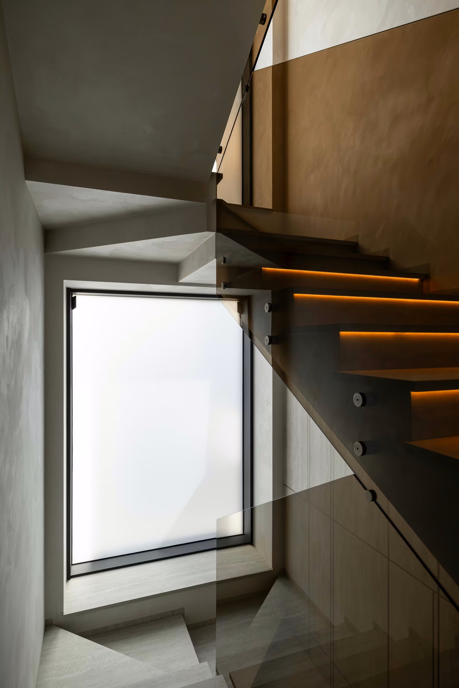 Fereastră cu aspect mat lângă scara interioară, cu balustradă din sticlă.