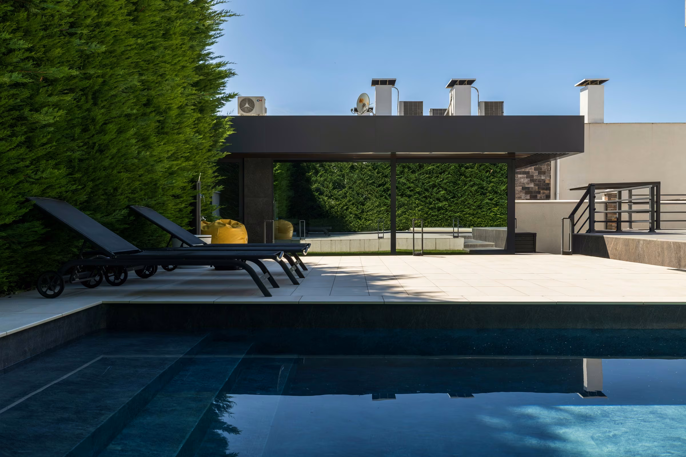 Exterior view of a contemporary terrace with panoramic glazing and landscaped surroundings.