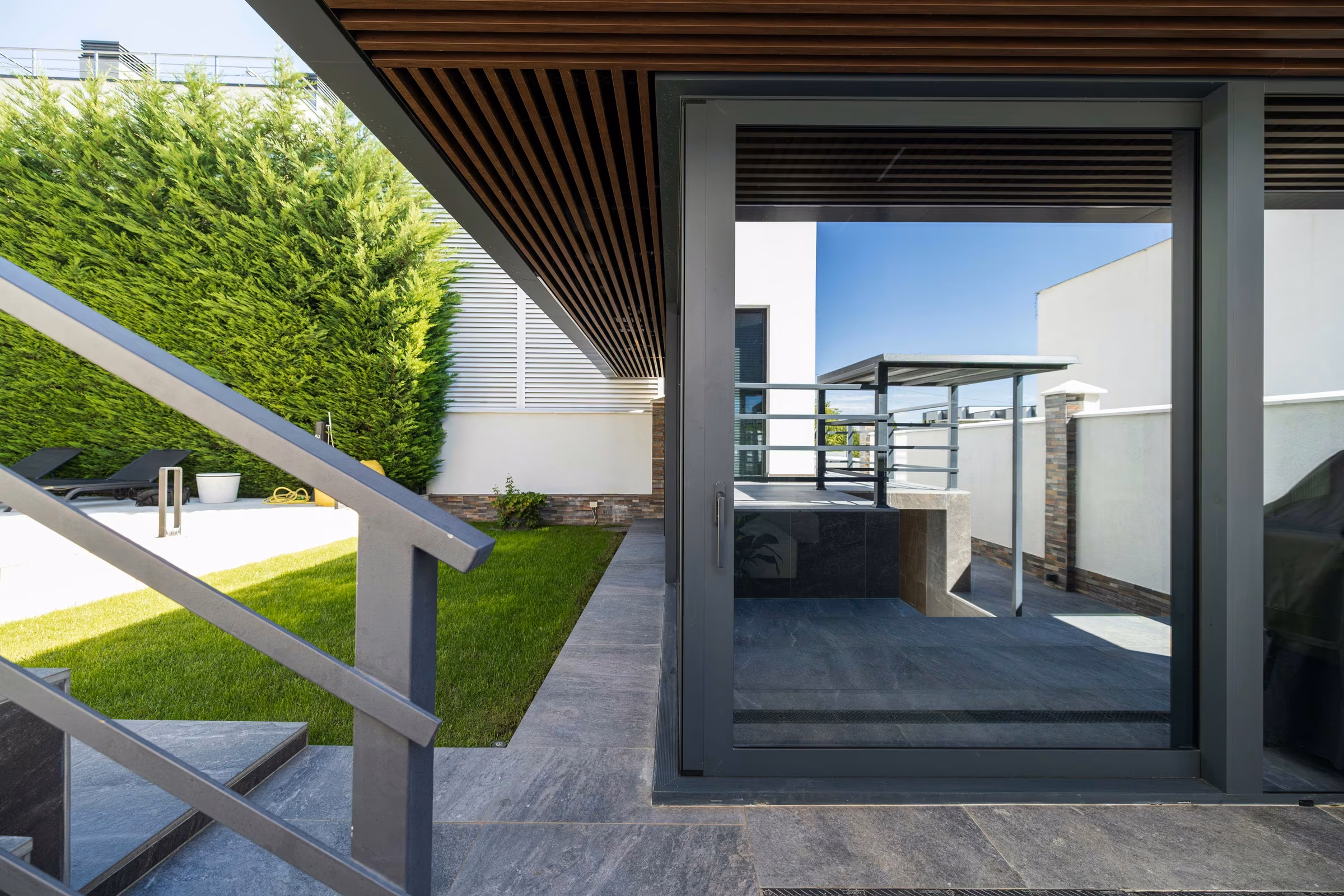 Architectural detail of a glazed opening with dark aluminium profiles.