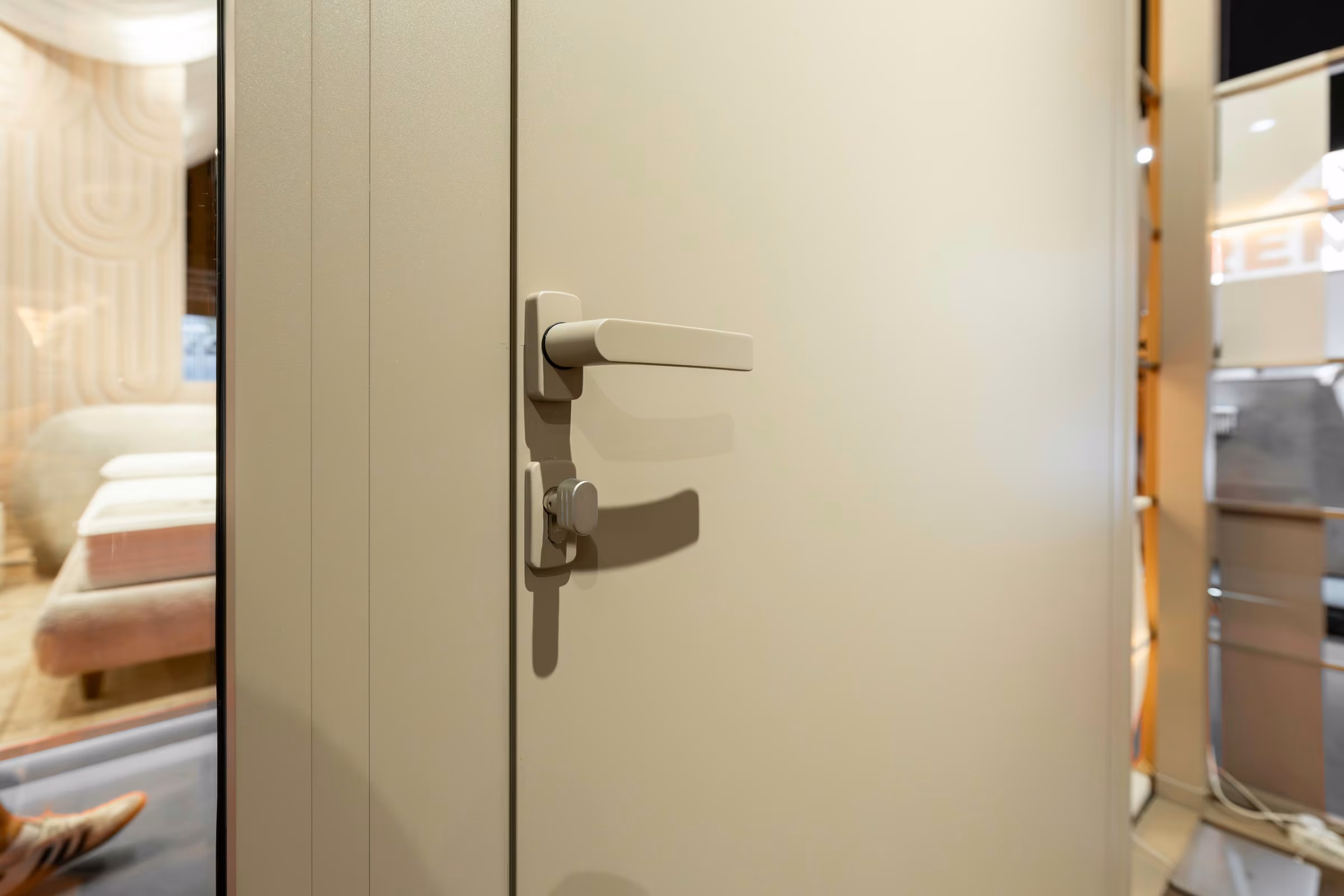 Detail of a light-coloured metal handle mounted on a smooth panel door.