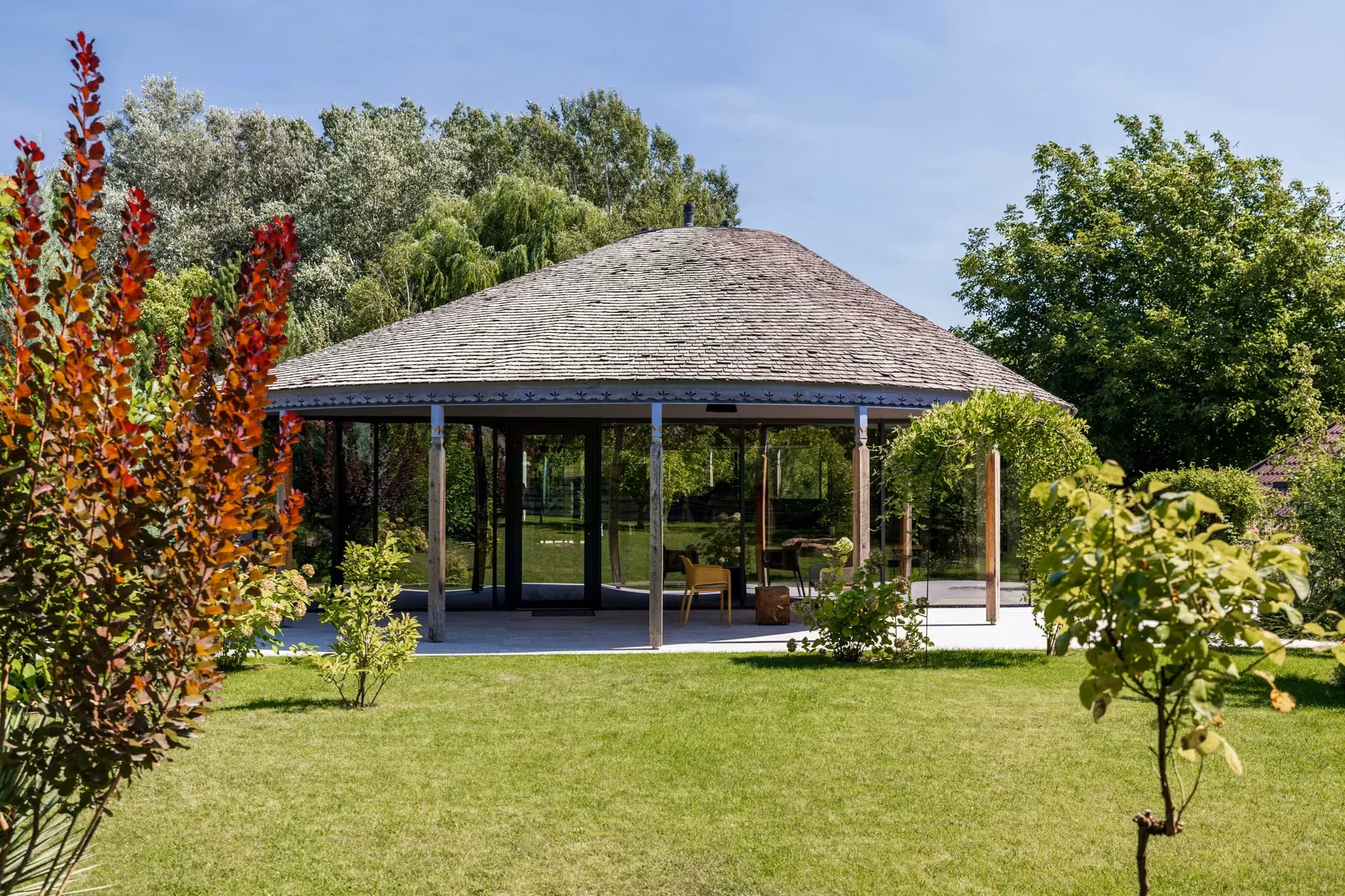 A home where expansive glass follows the architecture's lines, opening the interior towards the garden, natural light and the calm landscape of the nearby lake.