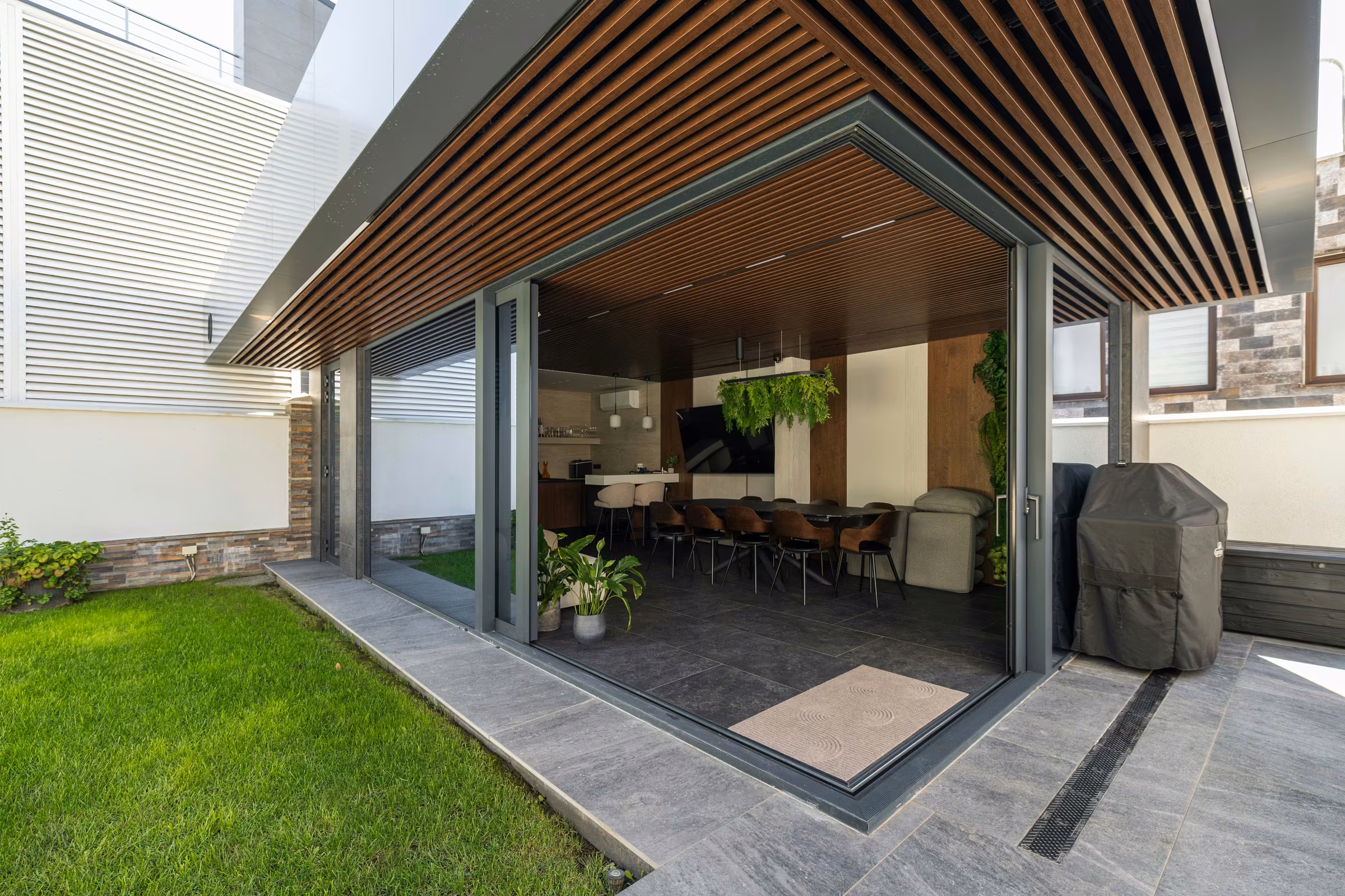 Contemporary terrace with panoramic glazing and dark aluminium frames.